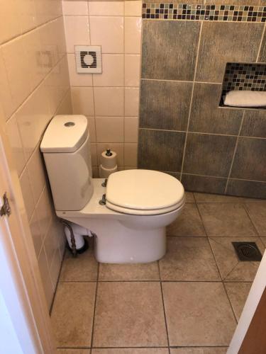 a bathroom with a toilet in a tiled room at Jo's House in Walsall