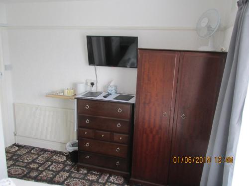 a bedroom with a dresser and a flat screen tv at Valdene Hotel in Paignton