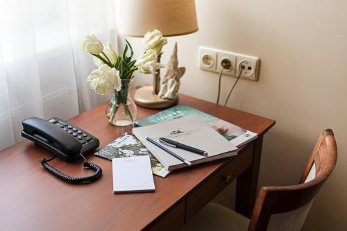 a desk with a telephone and a vase of flowers at Conviva in Panevėžys