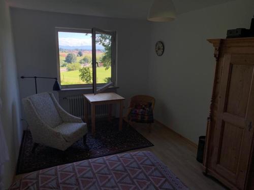 a living room with a chair and a window at Zimmer mit Bergblick in Starnberg