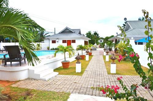a walkway next to a house and a swimming pool at Britannia Hotel in Grand'Anse Praslin