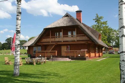 a large wooden house with a thatched roof at Vonadziņi in Stāmeriena