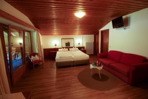 a hotel room with a bed and a red couch at Gästehaus Hochkönig in Filzmoos