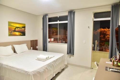 MauritiにあるHijo Buriti Hotelの白いベッドと窓のある寝室