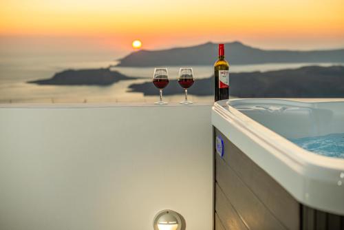two glasses of wine sitting on the edge of a bath tub at Caldera Stories private suites in Megalokhori