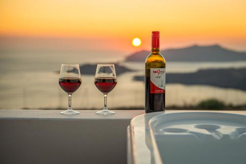 two glasses of wine sitting on a table with a bottle of wine at Caldera Stories private suites in Megalokhori