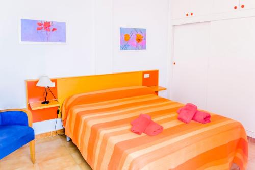 - une chambre avec un lit et 2 chaussons roses dans l'établissement SOL NAIXENT, à Fornells