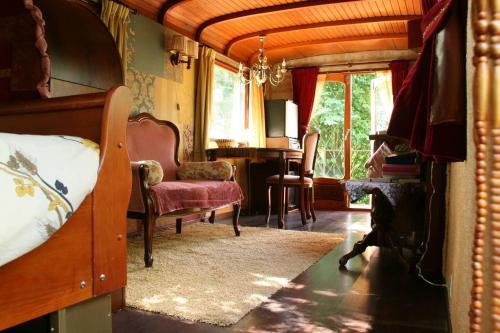 um quarto com uma cama, uma cadeira e janelas em Vegawagen Psyche, een sprookje in Coevorden em Coevorden