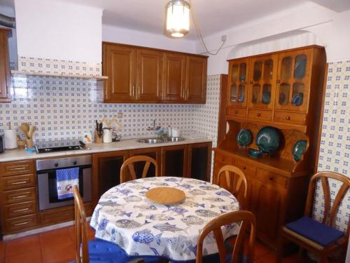 a kitchen with a table and a sink and a table and chairs at CASA BERIMBAU in Vila Nova de Milfontes