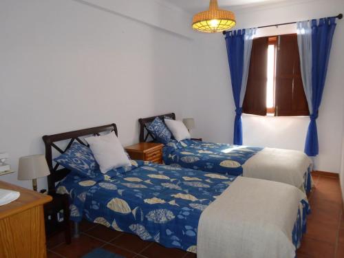 een slaapkamer met 2 bedden, een tafel en een raam bij CASA BERIMBAU in Vila Nova de Milfontes