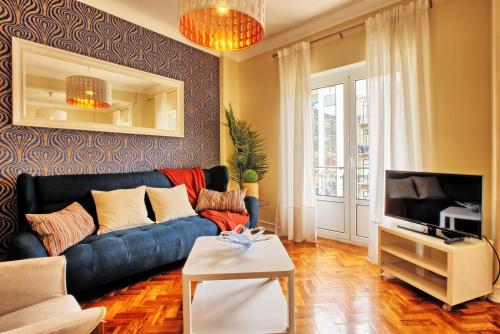 a living room with a blue couch and a tv at Almirante 3-Four Bedrooms in Lisbon