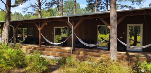 a house with a wrap around porch with hammocks at Cerību Liedags in Mērsrags