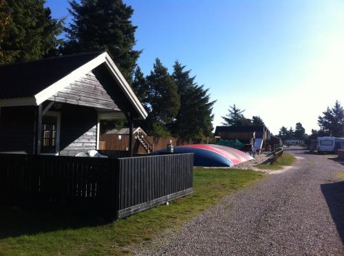 a small house with a fence next to a road at Vejers Family Camping & Cottages in Vejers Strand