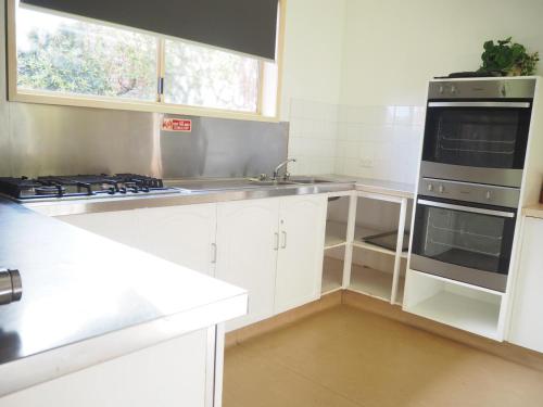 a kitchen with white cabinets and a stove top oven at BIG4 Tasman Holiday Parks - Warrnambool in Warrnambool