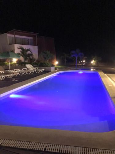 a large blue swimming pool at night at Las palmeras de bocapan in Tumbes