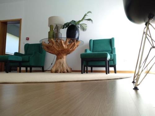 a living room with two green chairs and a table at Quinta Vale de Carvalho in Pinhal do Douro