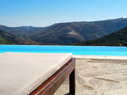 a pool with blue water and mountains in the background at Quinta Vale de Carvalho in Pinhal do Douro