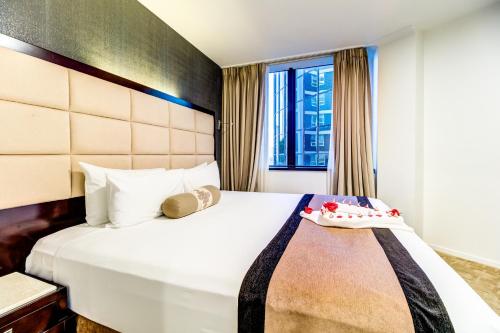 a bedroom with a large white bed with a window at VR Queen Street Hotel & Suites in Auckland