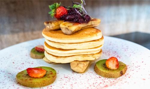 a stack of pancakes with strawberries on a plate at VR Queen Street Hotel & Suites in Auckland