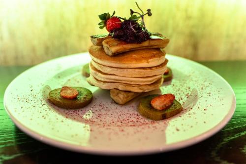 a stack of pancakes on a plate with a strawberry on top at VR Queen Street Hotel & Suites in Auckland