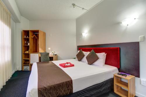 a bedroom with a large bed with a red headboard at Ascotia Off Queen in Auckland