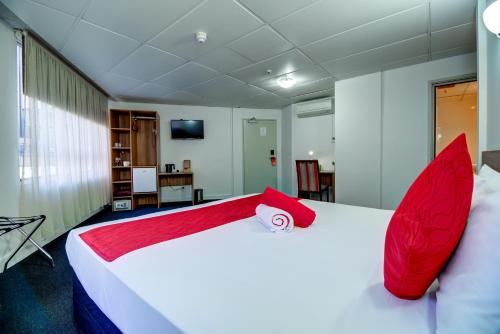 a bedroom with a large white bed with red pillows at Ascotia Off Queen in Auckland