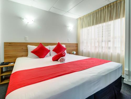 a bedroom with a large bed with red pillows at Ascotia Off Queen in Auckland