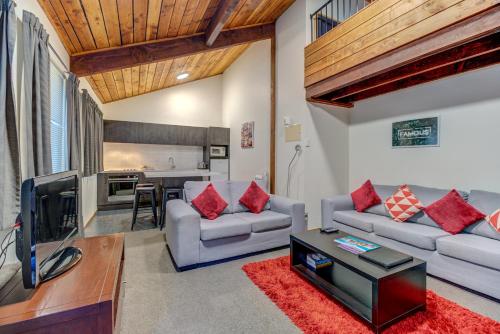 a living room with a couch and a tv at The Lofts Apartments in Queenstown