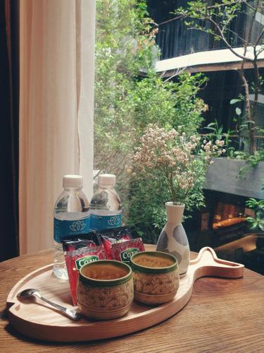 a tray with two cups of coffee on a table with a bottle at Minh Boutique in Da Nang