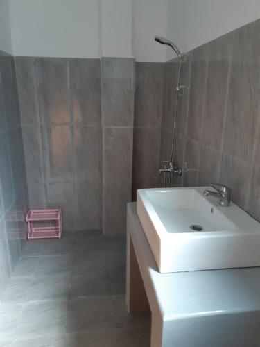 a bathroom with a white sink and a pink basket at Siril Guesthouse Hostel in Nuwara Eliya