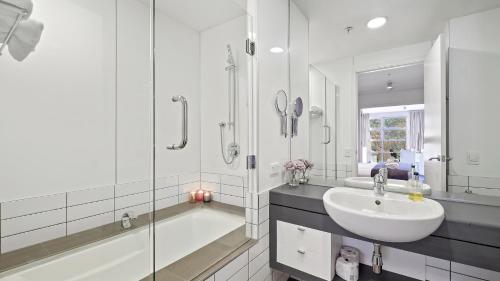 y baño con bañera, lavamanos y ducha. en Marina Apartment 406, en Queenstown