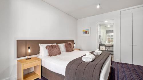 1 dormitorio con 1 cama blanca grande y baño en Marina Apartment 406, en Queenstown