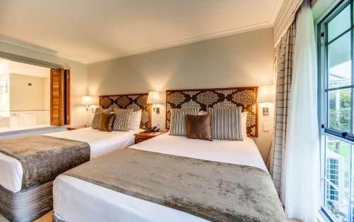 two beds in a hotel room with a window at VR Rotorua Lake Resort in Rotorua