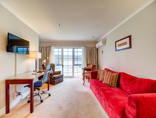 a living room with a red couch and a desk at VR Rotorua Lake Resort in Rotorua
