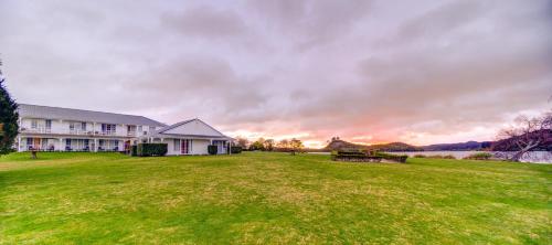 a house on a grassy field with a sunset at VR Rotorua Lake Resort in Rotorua