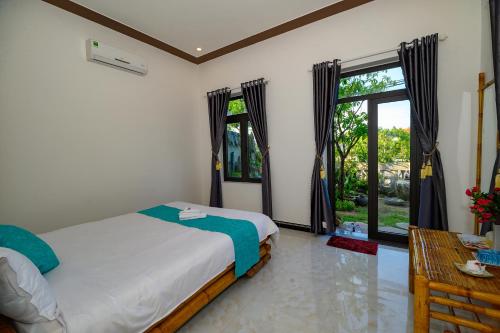 sypialnia z łóżkiem, stołem i oknem w obiekcie Hoi An Garden Sea Homestay w Hoi An