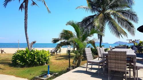 a table and chairs on the beach with palm trees at Luwansa Beach Hotel in Labuan Bajo