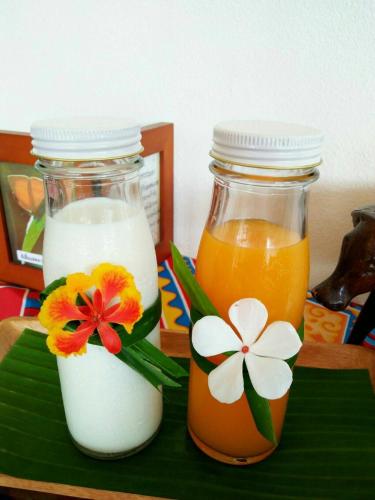 two jars of milk and orange juice on a table at Phunacome Resort in Dan Sai