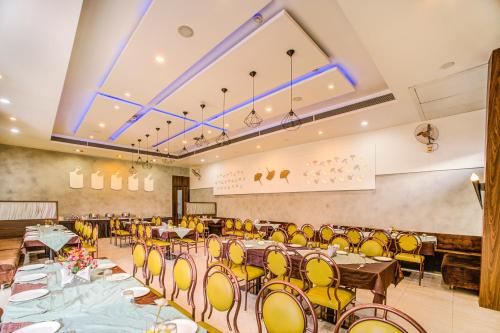 インドールにあるFabHotel Bee Townのテーブルと黄色い椅子が備わる宴会場