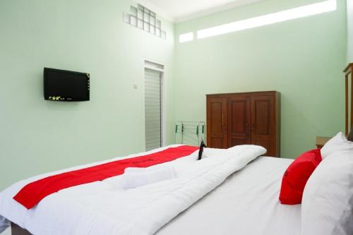 a bedroom with a large white bed with red pillows at RedDoorz Plus near Stadion Wijaya Kusuma in Cilacap