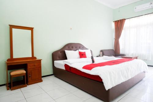 a bedroom with a bed and a dresser and a mirror at RedDoorz Plus near Stadion Wijaya Kusuma in Cilacap
