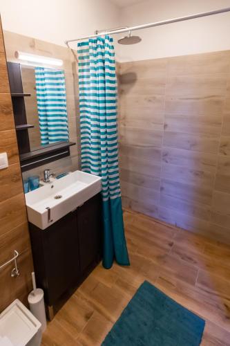 a bathroom with a sink and a blue shower curtain at Arya vila in Piešťany