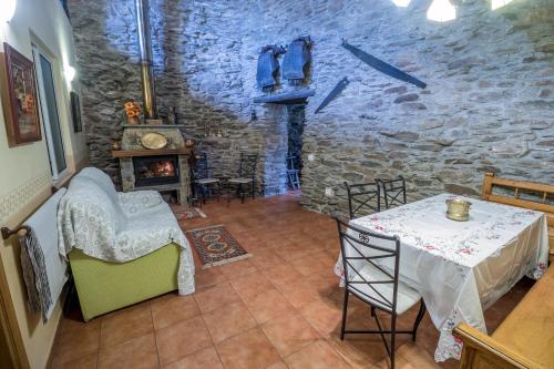 Cette chambre est dotée d'une table, de chaises et d'un mur en pierre. dans l'établissement Casa Rural La Fuente, à Tejedo del Sil