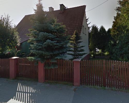 a fence in front of a house with a tree at Bajka in Gdańsk