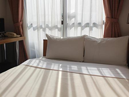 Una cama con almohadas blancas y una ventana en una habitación. en Hotel Tetora Ikebukuro, en Tokio
