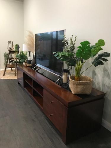 a living room with a large television on a wooden dresser at Executive Villa, private 2 bedroom in ideal location in Bathurst