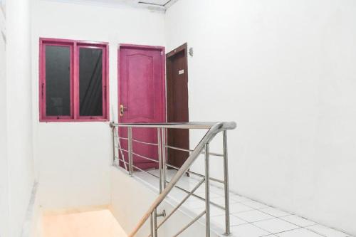 a room with a pink door and a ladder at RedDoorz at Pettarani Square Makassar in Makassar