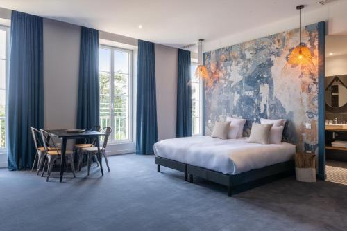 a bedroom with a bed and a table and chairs at Château de Tauzies, The Originals Relais in Gaillac