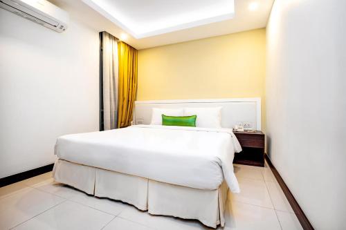 a bedroom with a large white bed with a green pillow at Becamex Hotel New City in Thu Dau Mot