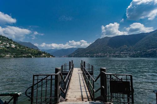 a dock on a lake with mountains in the background at Amazing Cernobbio - Lake Como by Rent All Como in Cernobbio